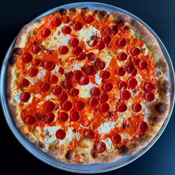 A whole pepperoni pizza with white cheese and red sauce on a metal tray.